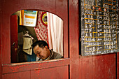 Man sitting in a booth next to the menu, canteen of the Xixiang Chi monastery, Emei Shan, Sichuan province, China, Asia