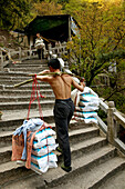 Porter carrying heavy load up stone stairs, Jiuhua Shan, Anhui province, China, Asia