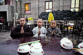 Young monks eating lunch, coal used cooking in the background, during birthday celebrations for Wenshu, Mount Wutai, Wutai Shan, Five Terrace Mountain, Buddhist Centre, town of Taihuai, Shanxi province, China