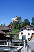 Fountain in the village of Sparsels with castle of Tarasp, Unterengadin, Grisons, Switzerland