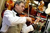 Musician playing on a violin in an Antique Violin repair shop, Old Town, Prague, Czech Republic
