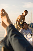 Group of young people sitting on jetty, laughing