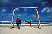 Älteres Paar schaukelt am Nordseestrand, Deutschland