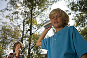 Two boys playing with a tin can phone, children's birthday party