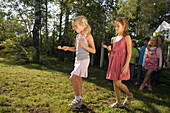 Two girls playing egg-and-spoon race, children's birthday party