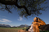 Young woman sitting on a bench enjoying the sunshine, Wals-Siezenheim Salzburg, Austria
