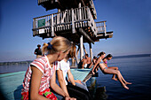 Girls jumping off into the lake from a wooden diving platform, Utting, Ammersee, Bavaria, Germany
