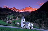 Kirche von St. Zyprian mit den Tschaminspitzen, Vajoletttürme und Königlaurinwand im Alpenglühen, Dolomiten, Südtirol, Italien