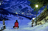 Sledging on illuminated toboggan-run at night, Alpendorf, St. Johann im Pongau, Salzburg, Austria