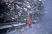 Person with sledge in front of Spielberghaus in snowstorm, Saalbach, Salzburg, Austria