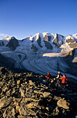 Three mountaineerers descending from summit of Munt Pers with view to Piz Palue and glacier of Pers, Pontresina, St. Moritz, Bernina, Oberengadin, Grisons, Switzerland