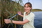 A woman paddling along reeds, Lake Labussee, Mecklenburg Lake District, Mecklenburg Western Pomerania, Germany