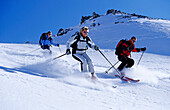 Drei junge Leute, zwei Frauen und ein Mann, fahren Tiefschnee im Skigebiet Parsenn, Davos, Klosters, Graubünden, Graubuenden, Schweiz, Alpen, Europa