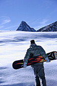 Person with snowboard walking through snow, Hintertux Glacier, Zillertal, Tyrol, Austria