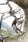 Three men climbing in a spiders web at Crazy Eddy in Silz, Haiming in the background, Tyrol, Austria