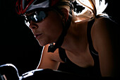 Female cyclist riding a bicycle, mirroring of an arrow in her sunglasses
