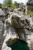 Maggia Schlucht, Kanton Tessin. Ein Mann in einem Neoprenanzug springt von einem hohen Felsen ins Wasser. Ponte Brolla, Valle Maggia, Südschweiz, Schweiz, Europa, MR