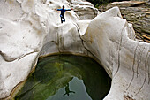 Maggia Schlucht, Kanton Tessin. Ein Mann in einem Neoprenanzug springt von einem Felsen ins Wasser. Ponte Brolla, Valle Maggia, Südschweiz, Schweiz, Europa, MR
