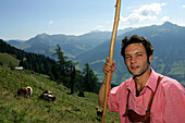 Dairyman  dressed in the typical alpine Style, looks after the young Cattle on the steep Meadows of the Viehausalm, Nationalpark Hohe Tauern, Salzburger Land, Austria