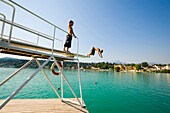 Boy jumping from diving platform into Worthersee, Velden, Carinthia, Austria