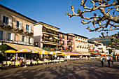 People passing pavement cafe of the Restaurant and Hotel Mövenpick Albergo Carcani at harbour promenade, Ascona, Lake Maggiore, Ticino, Switzerland