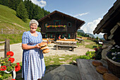 Eine Frau, Bäuerin, hält frisches Brot in der Hand, Amoseralm 1198 m, Dorfgastein, Gasteiner Tal, Salzburg, Österreich