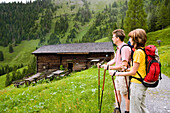 Couple hiking, arriving at Karseggalm, 1603 m, one of the oldest mountain huts in the valley, Grossarl Valley, Salzburg, Austria