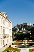 Tourists strolling through Mirabell gardens, Mirabell palace, Hohensalzburg Fortress, the largest fully preserved fortress in central Europe, in the background, Salzburg, Salzburg, Austria