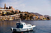 Motorboat anchoring in harbour Gialos, view to monastery Moni Evangelismos, Simi, Symi Island, Greece