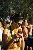 Young woman wearing sunglasses holding drinks, sunday party at Sundance Beach Bar, Gennadi beach, Gennadi, Rhodes, Greece