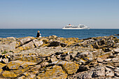 Frau auf Felsen blickt auf MS Europa, Gudhjem, Bornholm, Dänemark, Skandinavien, Europa