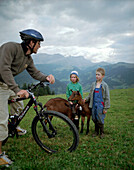 Mountenbiker, children guarding goats, over Simmervallley, near Lenk, Berner Alpen, Kanton Bern, Switzerland