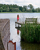 Frau steht auf einem Steg am See, Seehotel Neuklostersee, Nakenstorf, Mecklenburg-Vorpommern, Deutschland