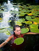 Woman bathing between water lilies, Hotel Neuklostersee, Nakenstorf, Mecklenburg-Western Pomerania, Germany