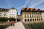 Woman with dog walking over bridge Rathaussteg, city hall at Rathausquai in background, River Reuss, Lucerne, Canton Lucerne, Switzerland