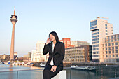 Junge Geschäftsfrau telefoniert im Medienhafen von Düsseldorf, Fernsehturm, Rheinturm, neuer Zollhof, Landeshauptstadt von NRW, Deutschland