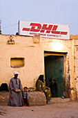 Three people sitting outside an express postal service shop, Theben, Luxor, Egypt