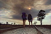 Two hikers walking along train tracks in the early morning