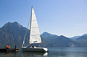 A couple sunbathing on a jetty next to a sailing boat, sailing on lake Traunsee, Upper Austria, Austria