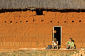 Two hikers having a rest at a typical hut, Madagascar, Africa