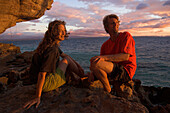 A couple sitting on rocks at dusk enjoying the view, Madagascar, Africa