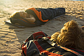 Young couple in sleeping bags at the beach