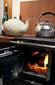 stove with wood fire and water kettle and tee pot, alpine hut in Upper Bavaria, Bavaria, Germany