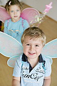 Children (3-4 years) wearing butterfly wings smiling at camera