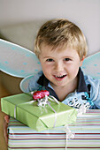 Junge (3-4 Jahre) mit Schmetterlingsflügel trägt Geschenke