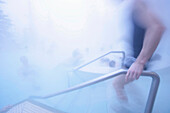 Young man entering hot water pool, Bavaria, Germany