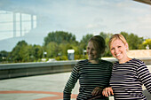 Smiling young woman leaning against a window, Luxembourg