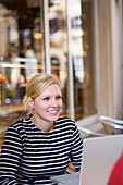 Junge Frau mit Laptop in Café, Luxemburg