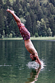 Young man jumping into a lake, Fuessen, Bavaria, Germany