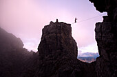 Young man balancing over a rope between to rocks, Oberstdorf, Bavaria, Germany